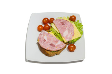 Tasty sandwich. slices of fresh bread with dried pork ham, green salad leaves and cherry tomatoes on white plate. isolated on white