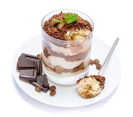 Classic tiramisu dessert in a glass cup on the plate and pieces of chocolate on white background with clipping path