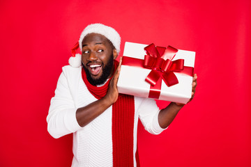 Portrait of amazed funky dark skin man wear santa claus headwear hold big package receive on x-mas...