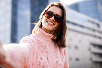 Fashion photo of beautiful young woman with sunglasses. City lifestyle. Female fashion. Closeup portrait. Beautiful reflection background.young lady making selfie.