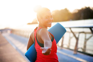 Woman smiling while walking to yoga in the morning