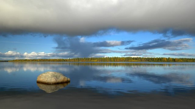 Zen landscape with stone, lake, autumn trees and clouds. North Finland, Lapland. 4K, UHD