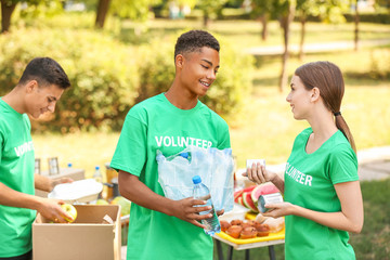 Young volunteers with food for poor people outdoors