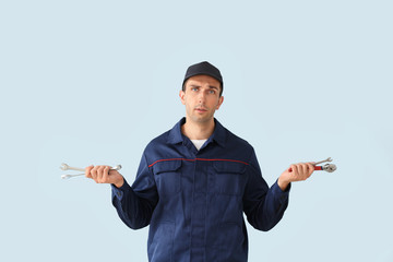 Confused car mechanic on color background