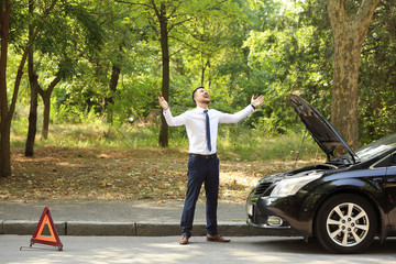 Stressed businessman near broken car outdoors
