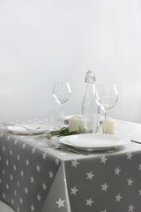 festive table setting with white plates and glasses on a gray tablecloth.