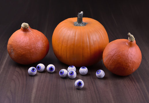 Halloween pumpkin with eyes stock images. Three halloween pumpkins with chocolate eyes. Creepy halloween pumpkin on a wooden background