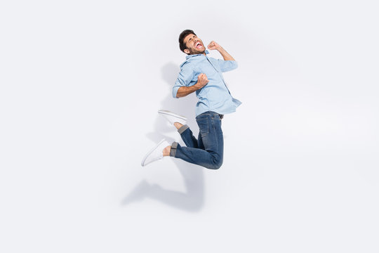Full body profile photo of multiethnic guy jumping high rejoicing of great win raising arms screaming wear casual denim outfit isolated white color background