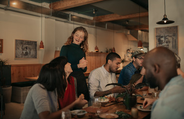 Friendly bistro waitress talking with a table of smiling customers