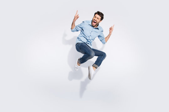 Full body photo of funny arabian guy jumping high rejoicing at hard rock concert making finger horns symbol wear casual denim clothes isolated white color background