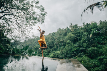 Woman enjoying tropical rain while on infinity pool on Bali