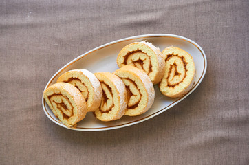 Slices of biscuit roll with apricot jam on a white plate