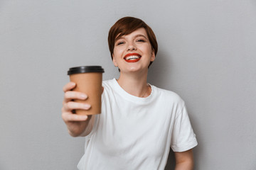 Image of young brunette woman smiling and holding takeaway coffee cup