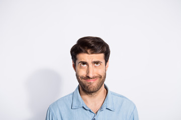 Photo of amazing mixed race guy looking up empty space making fake smile seeing terrible high shopping prices wear casual denim shirt isolated white color background