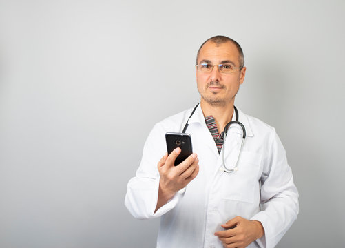Male doctor is typing a text message on a mobile phone