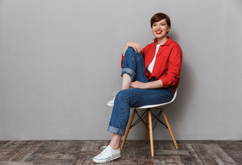 Image of happy young woman smiling while sitting on chair