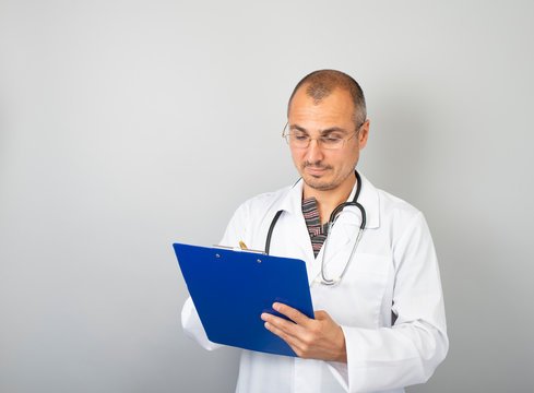 male doctor with a stethoscope around his neck holding documents in his hand