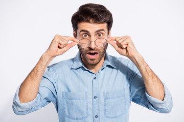 Naklejka premium Closeup photo of handsome indian guy not believe eyes staring on awful bad news on television wear specs casual denim shirt isolated white color background