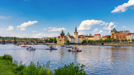 Smetanovo Embankment with Charles Bridge and boats on Vltava river, Prague, Czech Republic. Embankment of the Vltava river in Prague, the capital of Czechia.
