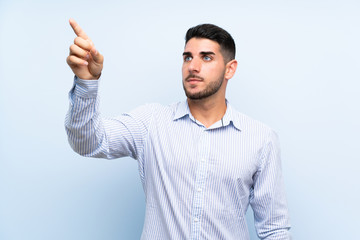 Fototapeta premium Caucasian handsome man over isolated blue background touching on transparent screen