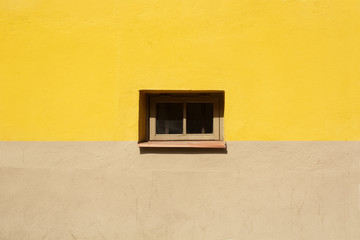 Colorful wall fragment with small window in the middle background. Yellow and beige house wall on...
