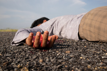 Concept of Crime scene ,Selective focus to victim hand with blood of a dead body lying on Road