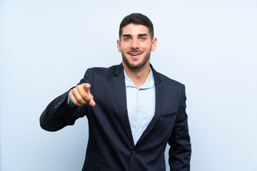 Handsome man over isolated blue background surprised and pointing front