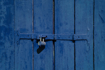 Old blue color wooden locked door texture background. Door with old metal lock. Close up