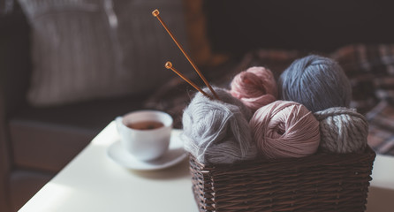 Woolen yarn and knitting needles in basket and tea