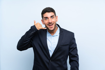 Handsome man over isolated blue background making phone gesture. Call me back sign