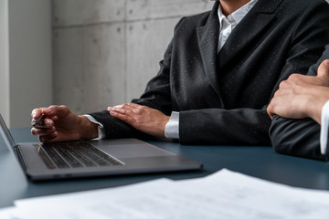 Hands of African businesswoman and Caucasian businessman discussing work at loft office table with laptop. Concept of diverse company and startup