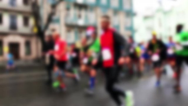 Closeup view of many blurry silhouettes of people running outdoors by city streets during charity City Marathon. Participants athletes run a long distance through the streets of the city. Slo-mo.