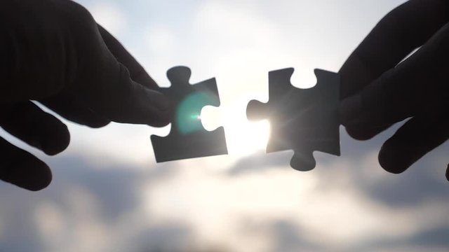 teamwork business finance concept. male hands connect two puzzles silhouette against the sunset. symbol lifestyle teamwork of association and connection. strategy business