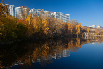 Fototapeta na wymiar Modern buildings on a background of blue sky, yellow trees and a lake.