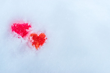 Two red heart lies in the snow. Concept February 14th.