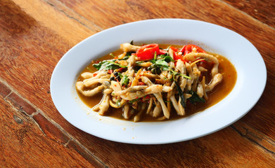 Fried stir spicy Razor clams with chilli and basil, Seafood in a white dish on brown wooden table,...