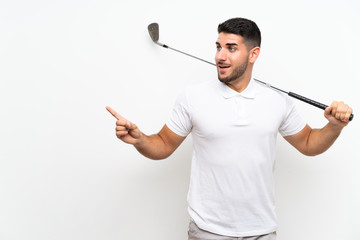 Handsome young golfer player man over isolated white background surprised and pointing finger to the side