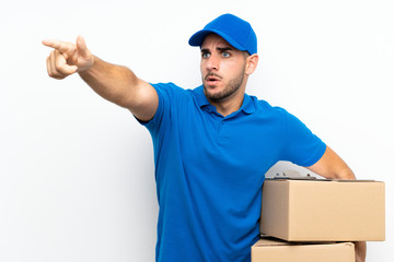 Delivery man over isolated white background pointing away