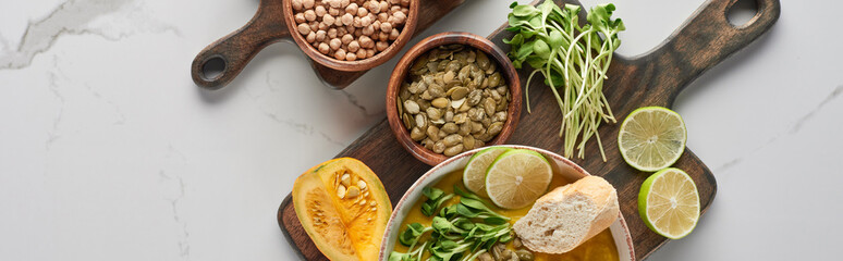 panoramic shot of autumnal mashed pumpkin soup on wooden cutting board on marble surface