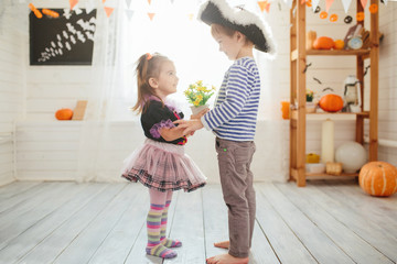 Boy in a pirate costume and a girl in a witch costume celebrates Halloween at home. A boy gives...