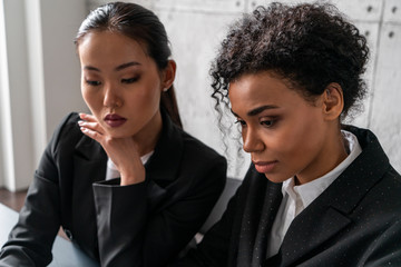 Concentrated young Asian and African women working together in office. Concept of diversity, education and teamwork