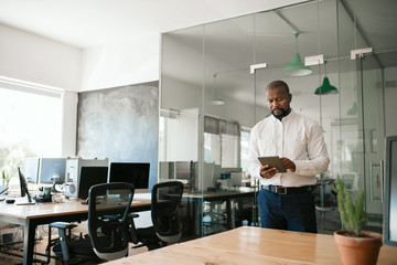 African American businessman standing in an office using a tablet