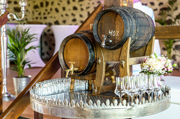 Old oak barrel with whiskey spirit small glases on a wooden table. in front of blurred background party station setting
