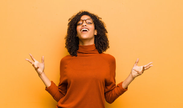 Young Pretty Black Woman Performing Opera Or Singing At A Concert Or Show, Feeling Romantic, Artistic And Passionate Against Orange Wall