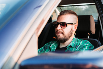 Cute, bearded man with eyeglasses driving a car. Transportation concept