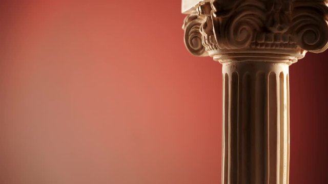 Single ancient greek column rotating slowly on dark orange color background, copy space text area