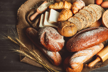 Different kinds of bread with nutrition whole grains on wooden background. Food and bakery in...