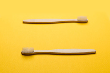 Bamboo toothbrushes on yellow background, top view