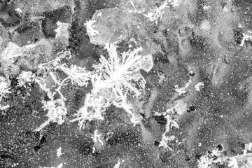 A monochrome close-up of the texture background of winter frozen river ice