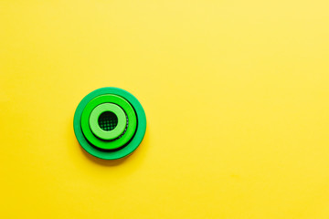 Geometry. Three green circles stack each in other on bright yellow background. Minimalism. Creative abstract concept. Educational wooden toys for children, learning shapes, sizes and colours shades